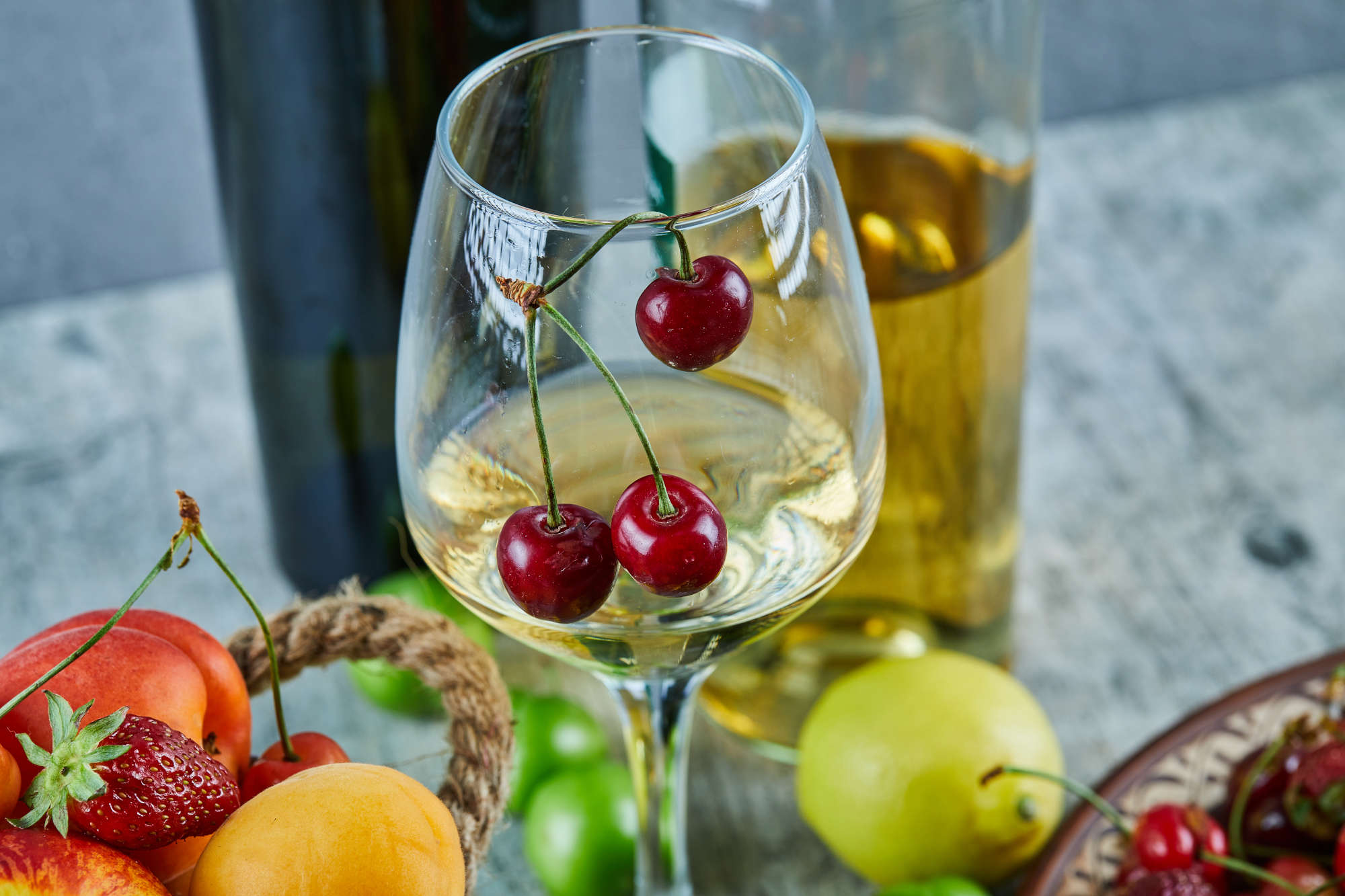 A bucket of summer fruits and citrus next to a glass of white wine — training your nose on everyday smells builds your wine tasting vocabulary