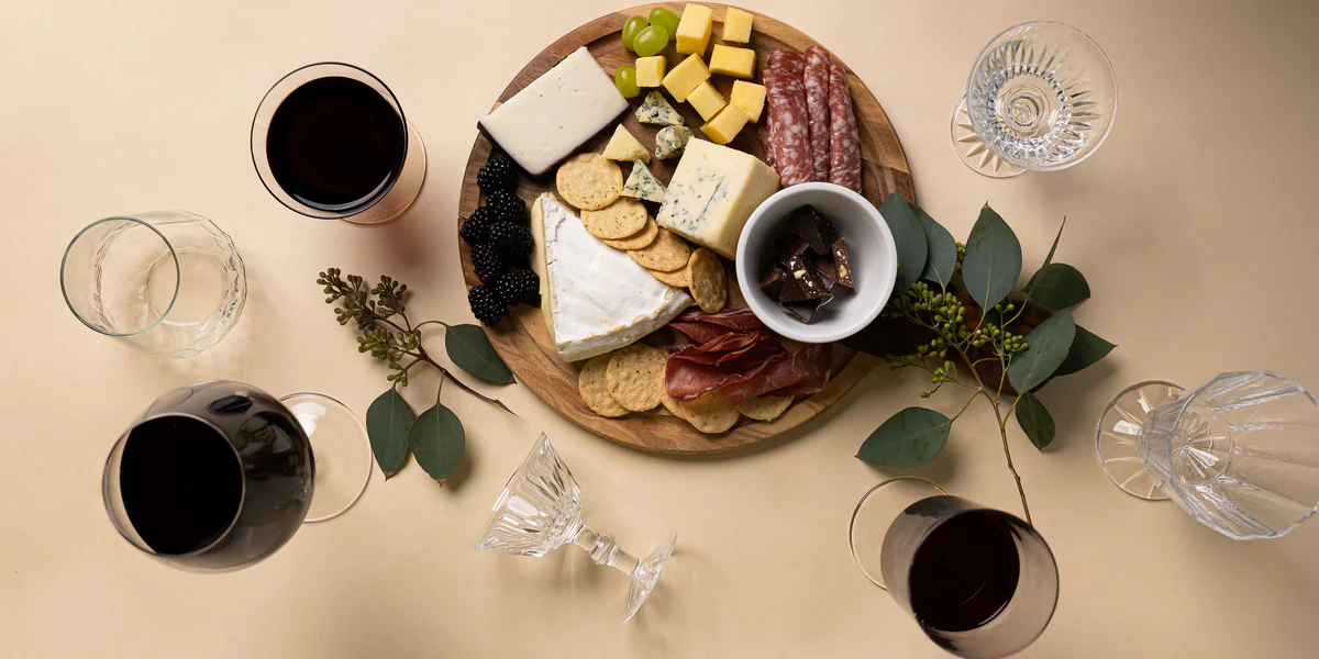 A cheese board with wine glasses alongside — goat cheese is one of the most wine-friendly cheeses thanks to its natural acidity and clean, tangy character