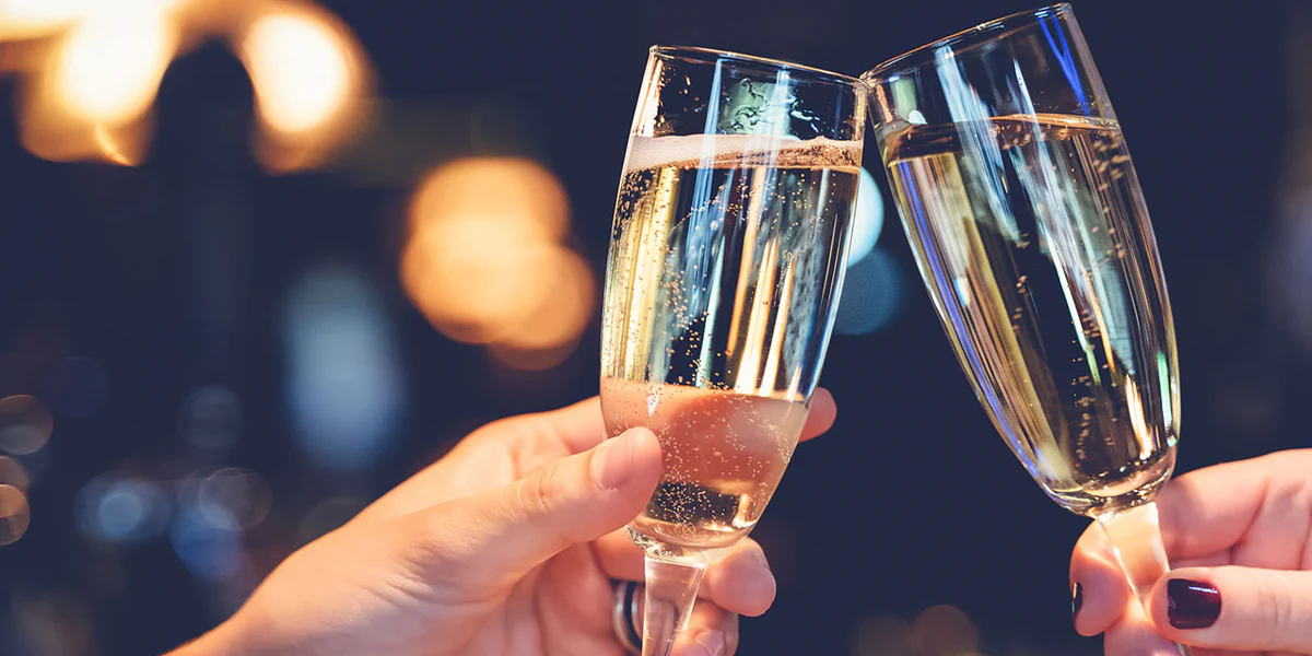 A couple toasting with sparkling wine glasses in a vineyard — Prosecco, Champagne and Cava are the three most popular choices for a celebration