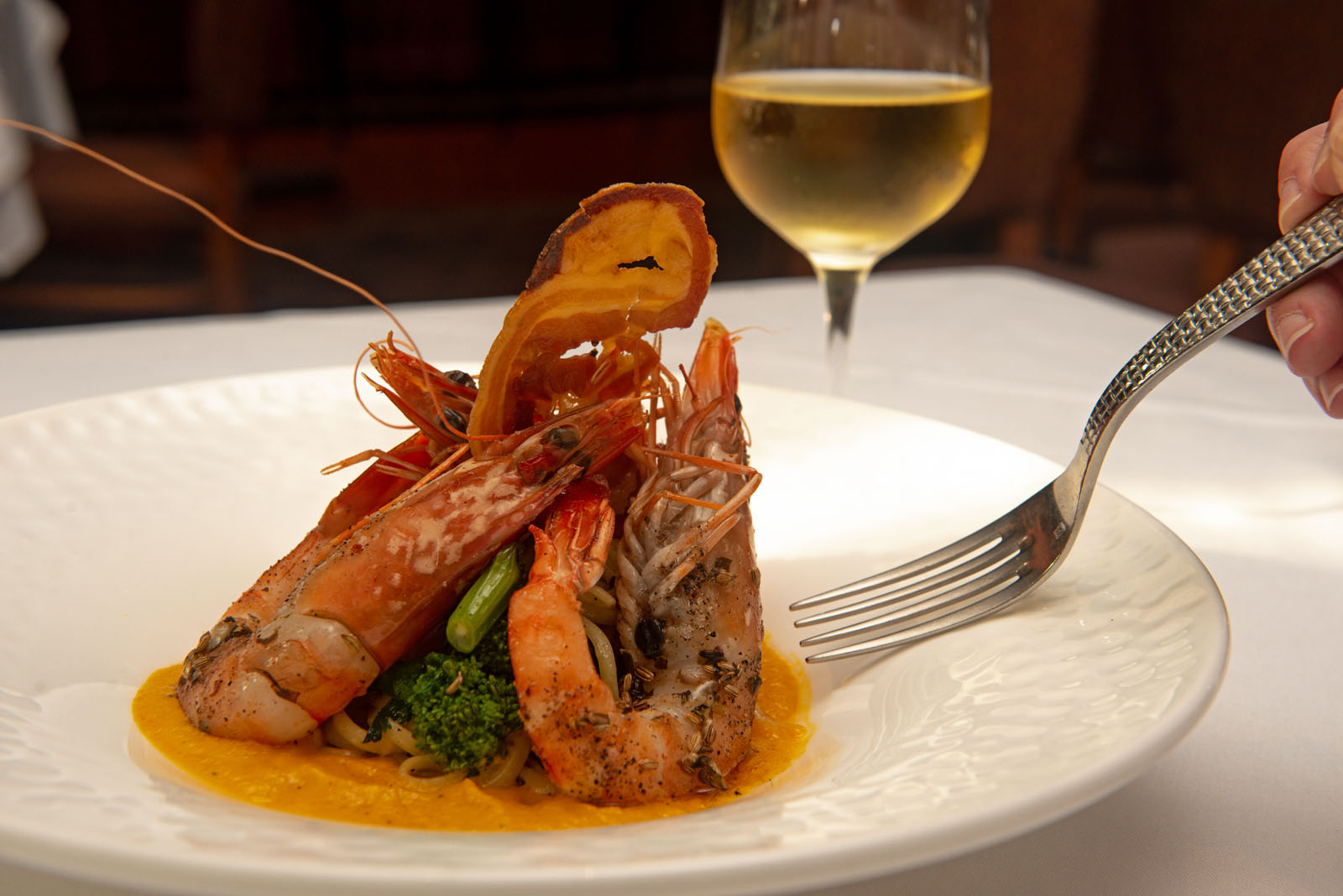 Pan-fried prawns served with herbs and a glass of white wine — Chardonnay's acidity and body make it one of the most reliable white wines for fish dishes