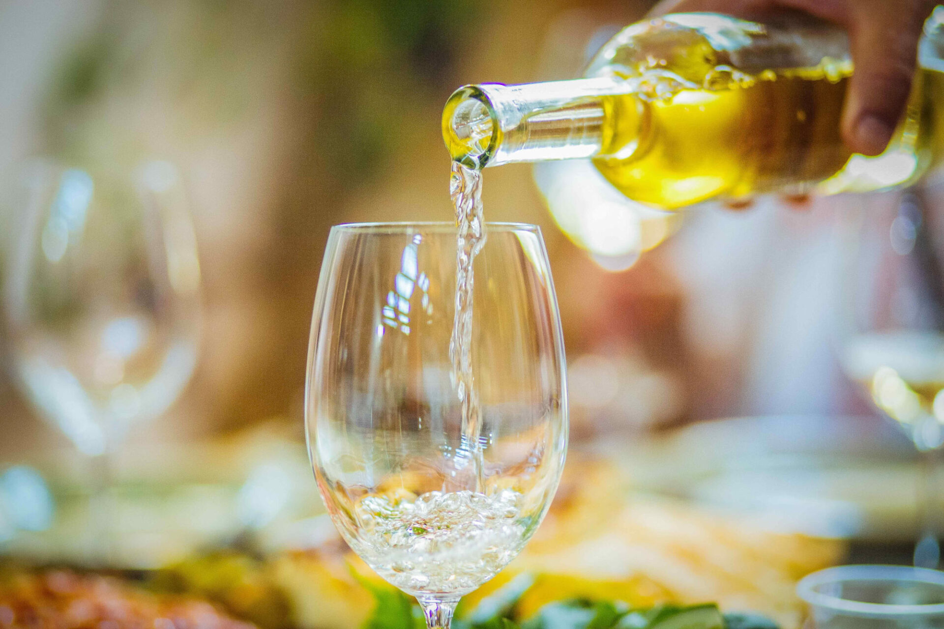 Pouring white wine into a glass from a bottle — how long does wine last once opened?