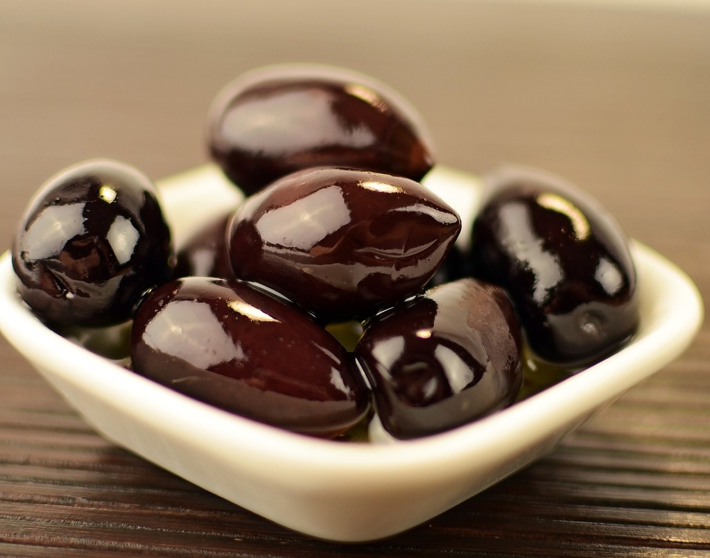 Olives and tapas on a wooden board alongside a glass of wine — the Spanish tapas tradition naturally pairs olives with Fino Sherry, Cava and Albariño
