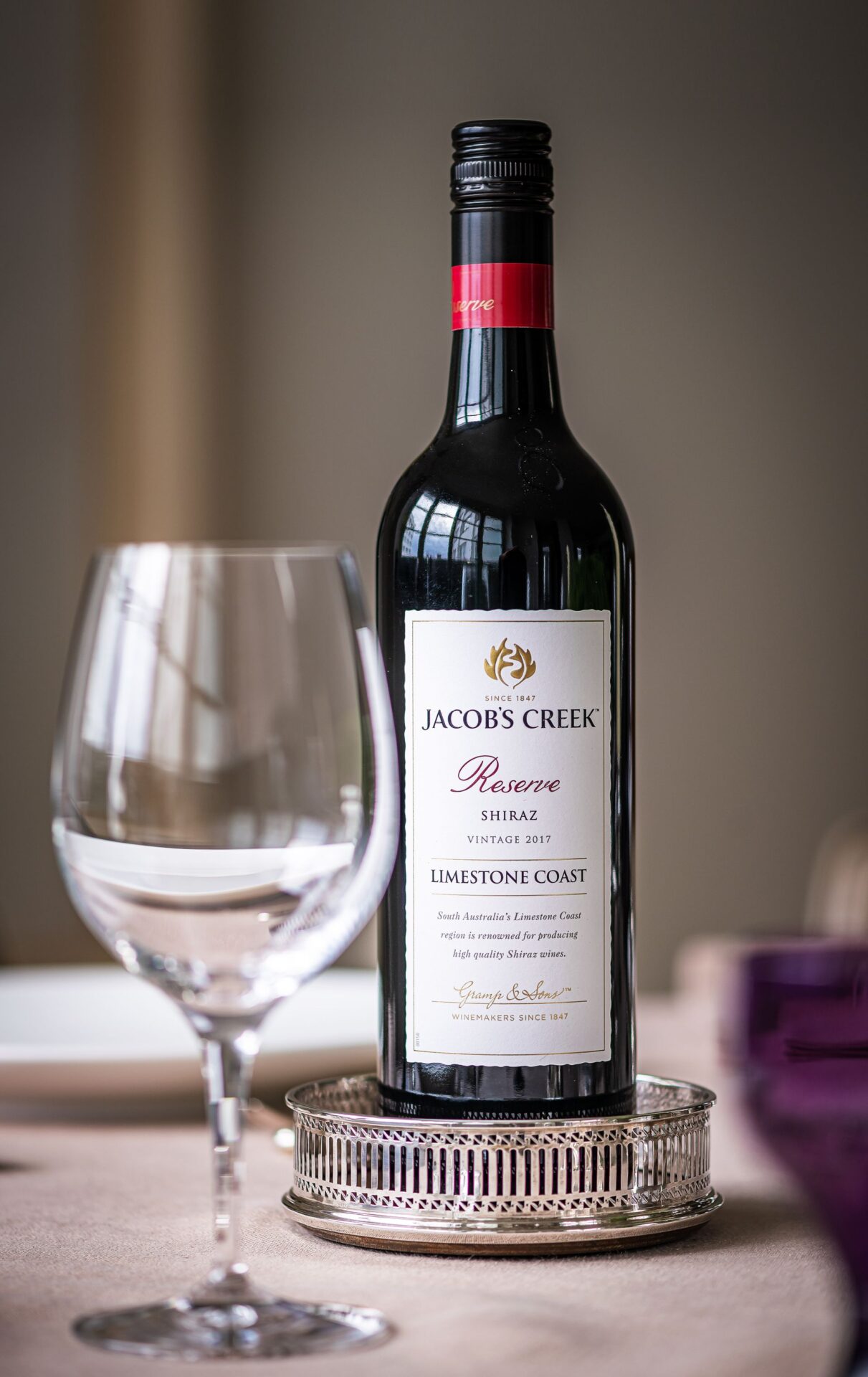 A hand holding a wine glass up to the light — describing wine well starts with looking at its colour before moving on to aromas and flavours