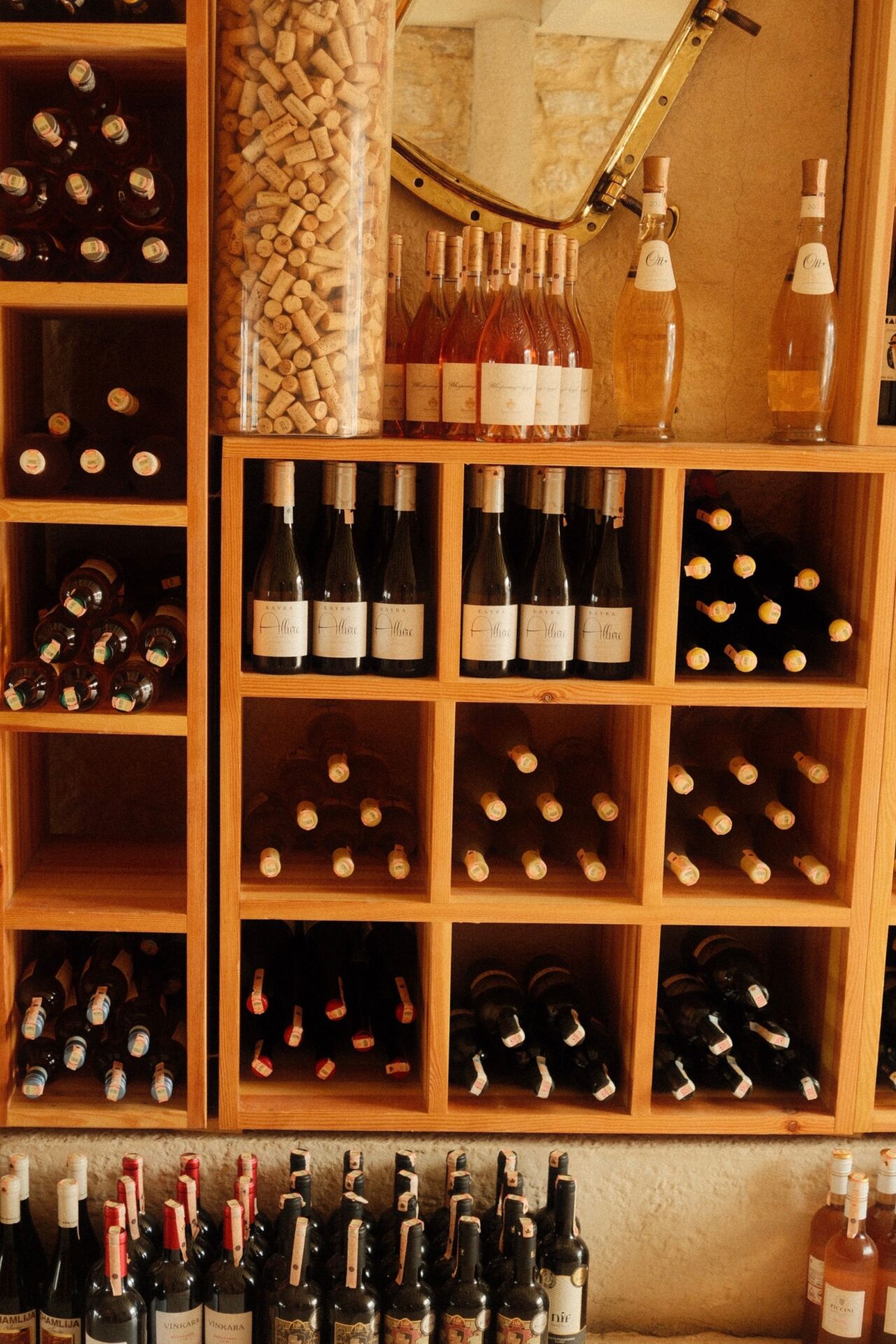A wooden wine rack holding diverse bottles across many wine types