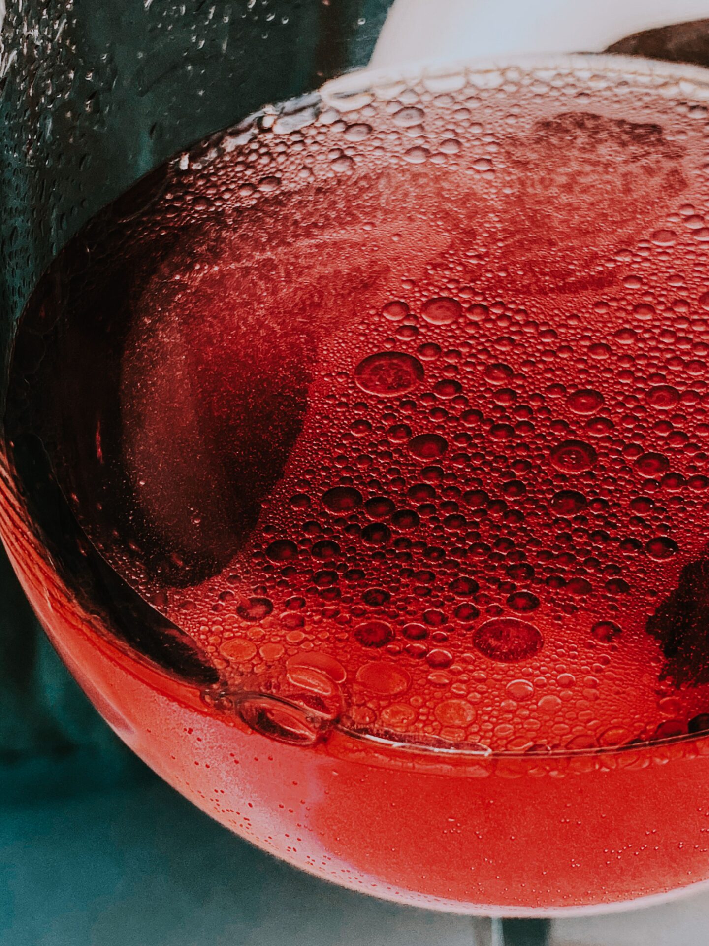 A glass of pink sparkling wine with visible bubbles, poured casually at the table