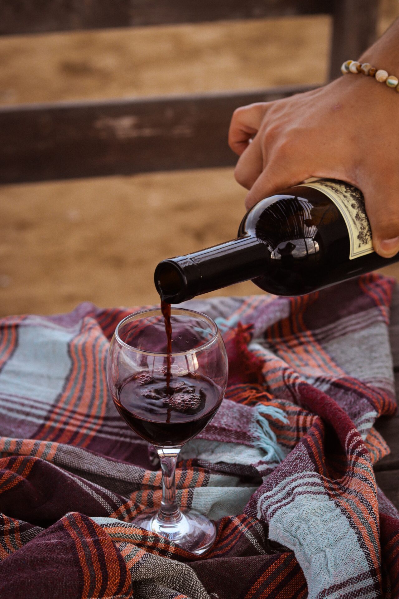 A hand pouring red wine, the first step in decanting a bottle