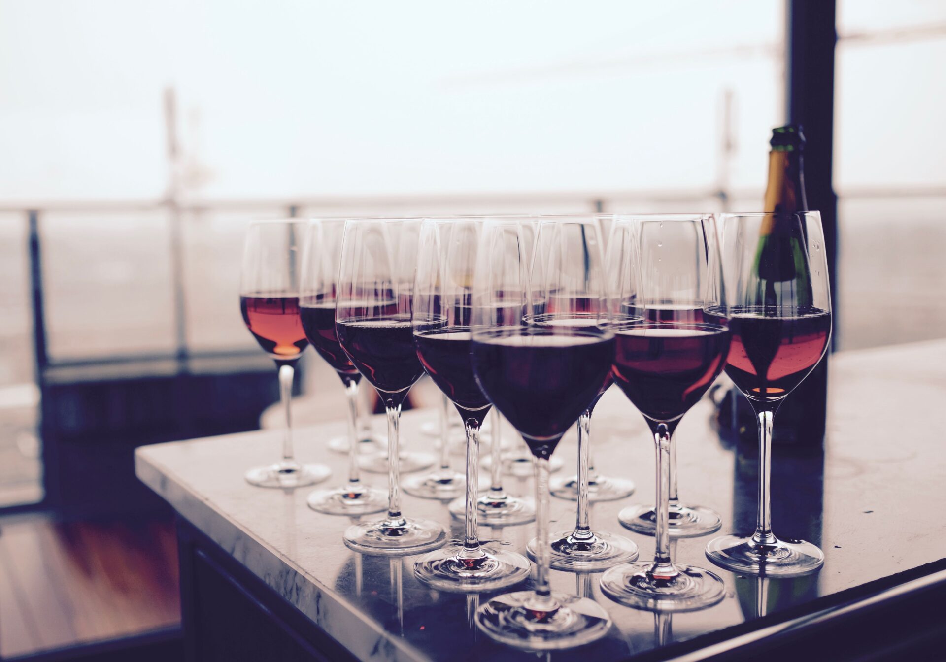 A row of wine glasses showing different wine colours from pale white through pink rosé to deep red — the six main types of wine covered in this guide