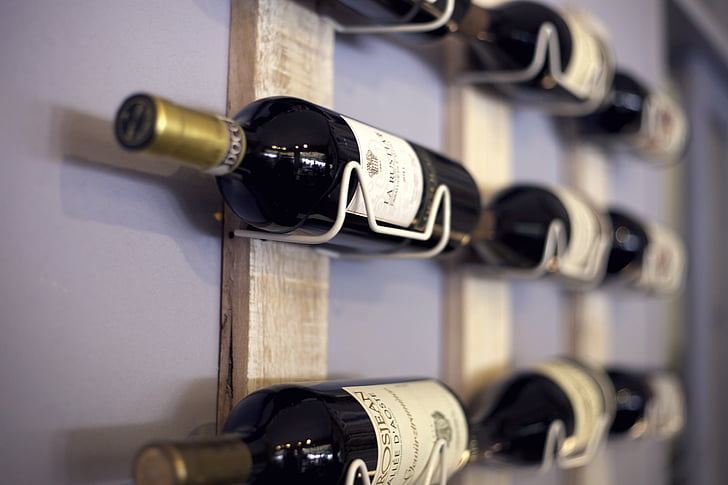 Wine bottles stored horizontally on a rack — lying wine on its side is essential for cork-sealed bottles, keeping the cork moist and preventing premature oxidation